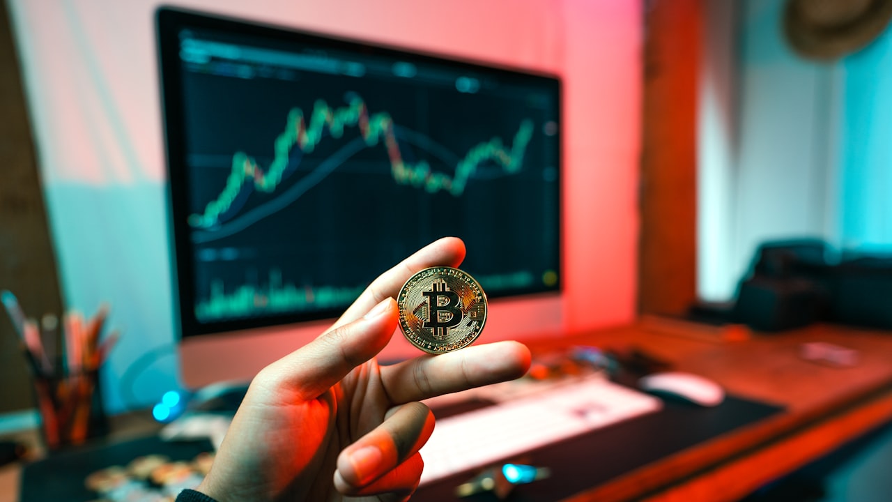 a person holding a coin in front of a computer