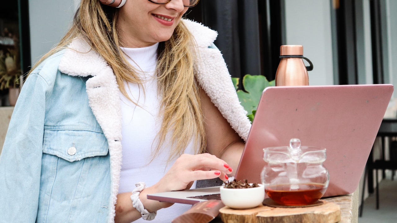 woman in white cardigan holding a silver fork and a glass of drink