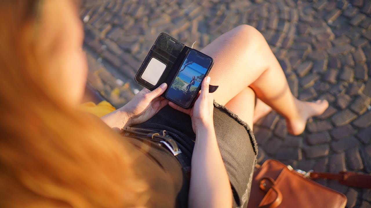 person in brown shorts holding black smartphone