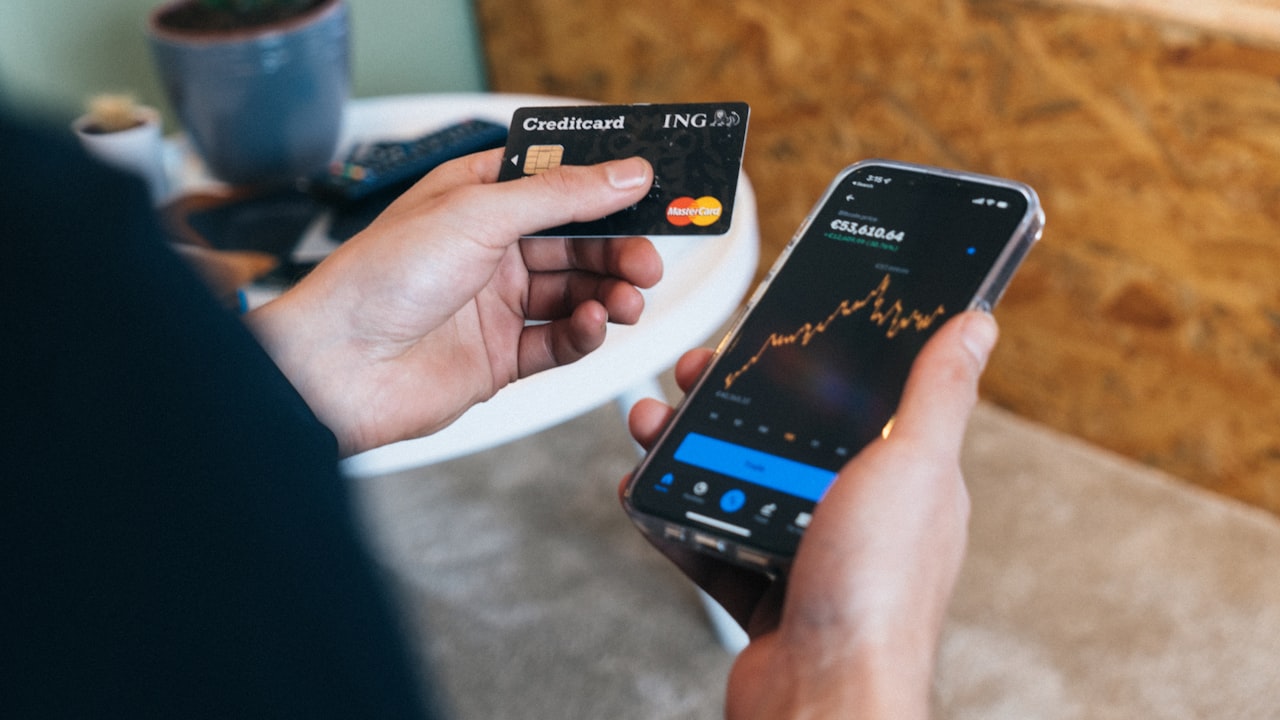 a person holding a smart phone and a credit card