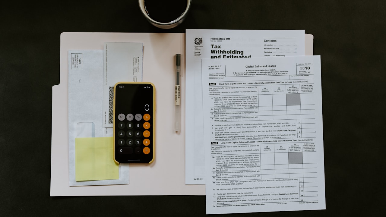 black Android smartphone near ballpoint pen, tax withholding certificate on top of white folder